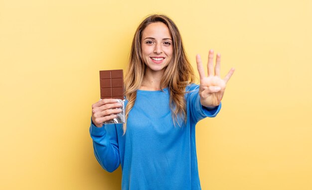 Jolie femme souriante et sympathique montrant le concept de chocolat numéro quatre