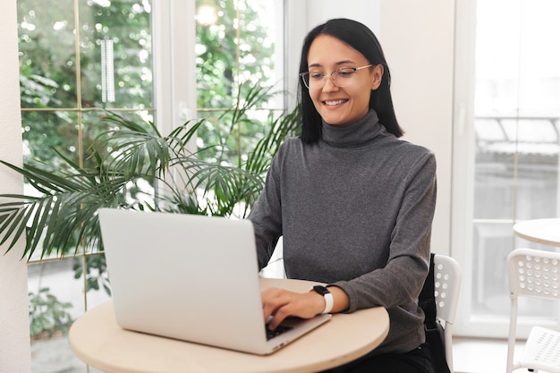 Jolie femme souriante travaillant sur ordinateur portable au café