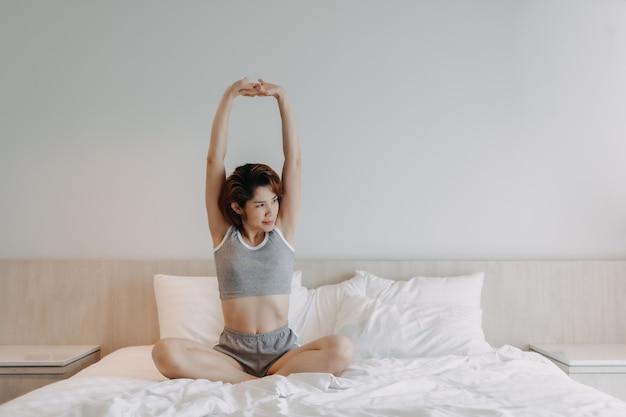 Jolie femme en sous-vêtements qui s'étend sur le lit le matin