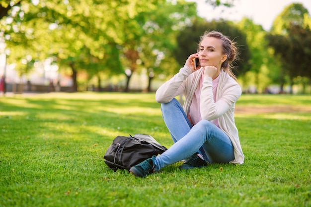 Jolie femme spaeking sur téléphone mobile dans une atmosphère agréable à l'extérieur au parc