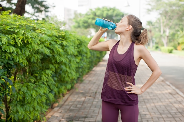 Jolie femme sportive, boire de la bouteille à l&#39;extérieur