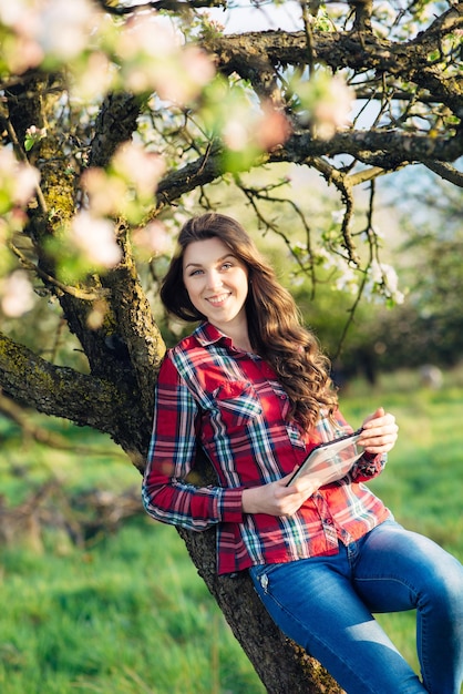 Jolie femme avec tablette dans un jardin fleuri