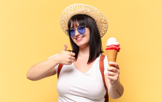 Jolie femme taille plus avec des lunettes de soleil, de la glace et un chapeau en vacances