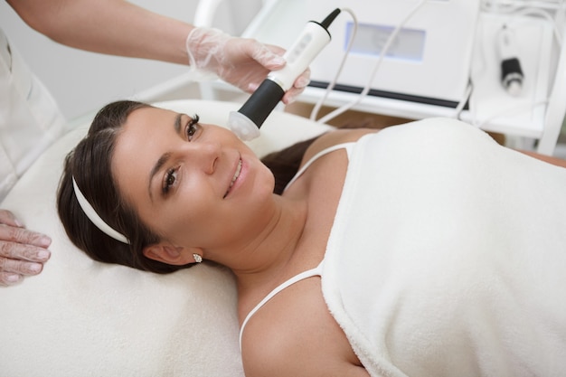 Jolie femme de taille plus souriante, obtenant un soin du visage par un cosméticien professionnel