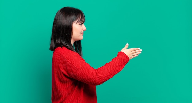 Jolie femme taille plus souriante, vous saluant et offrant une poignée de main pour conclure un accord réussi, concept de coopération