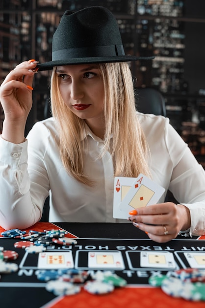 Photo une jolie femme tenant deux as et jouant au poker à la table du casino