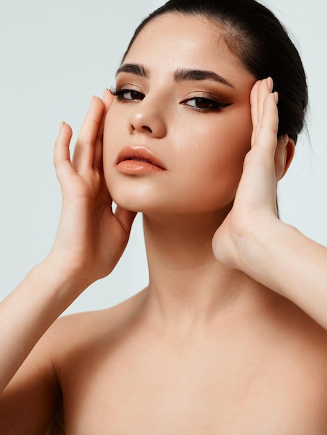 Jolie femme tenant ses mains près des tempes sur un modèle de coiffure de fond clair Photo de haute qualité