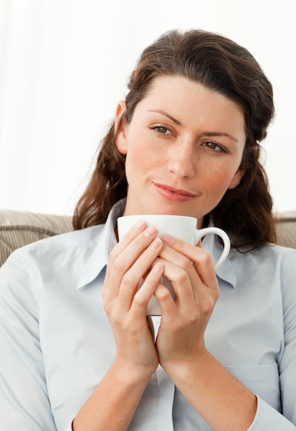 Jolie femme tenant une tasse de café, assis sur le canapé