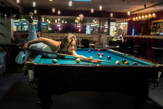 Jolie femme tenir la queue et jouer au billard