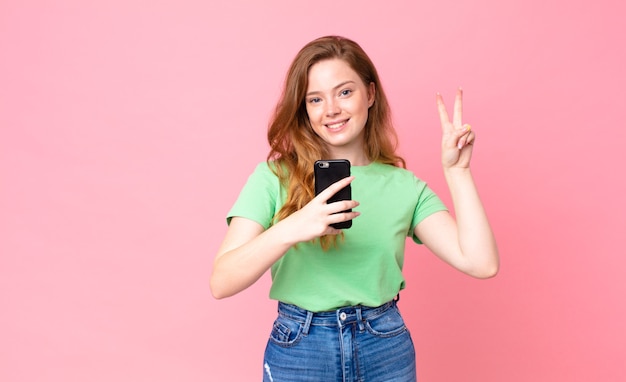 Jolie femme à tête rouge à l'aide de son téléphone intelligent