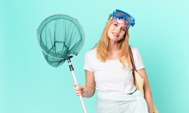 Photo jolie femme à tête rouge avec un filet de pêcheur et des lunettes.