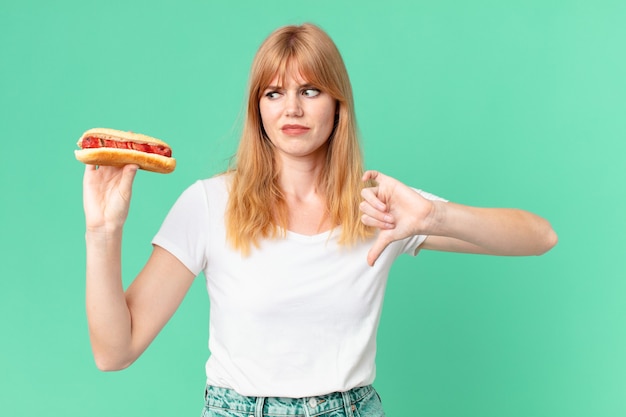 Jolie femme tête rouge tenant un hot-dog.