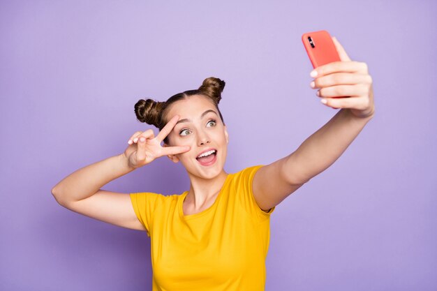 Jolie femme avec topknots posant contre le mur violet