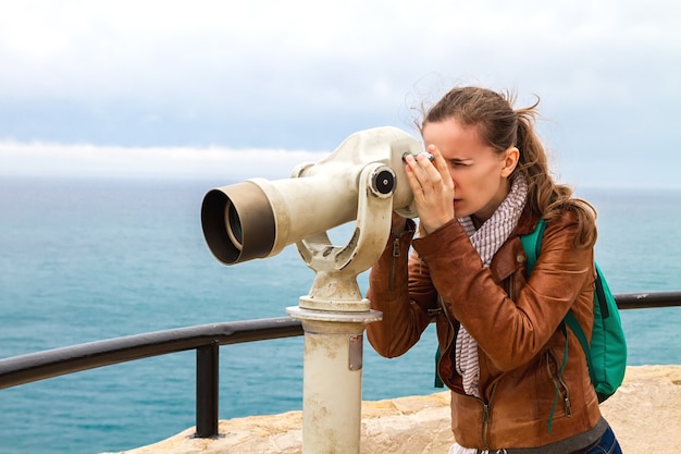 Photo la jolie femme le touriste dans les montagnes à la recherche de jumelles.