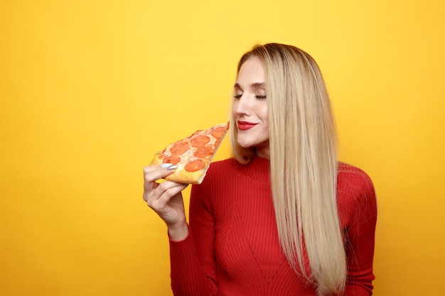 Jolie femme avec tranche de pizza isolée sur jaune