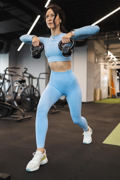 Jolie femme travaillant avec kettlebell au gymnase