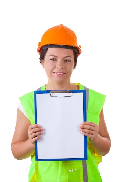 Jolie femme travailleuse en veste de sécurité et casque jaune tenant le presse-papiers avec du papier blanc sur fond blanc