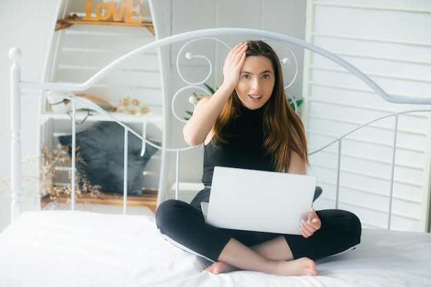 jolie femme utilisant un ordinateur portable et souriant le matin