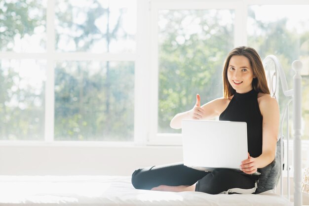 jolie femme utilisant un ordinateur portable et souriant le matin