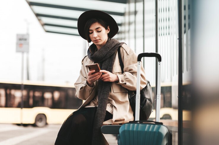 Photo jolie femme utilise un téléphone assis à un arrêt de bus de la ville