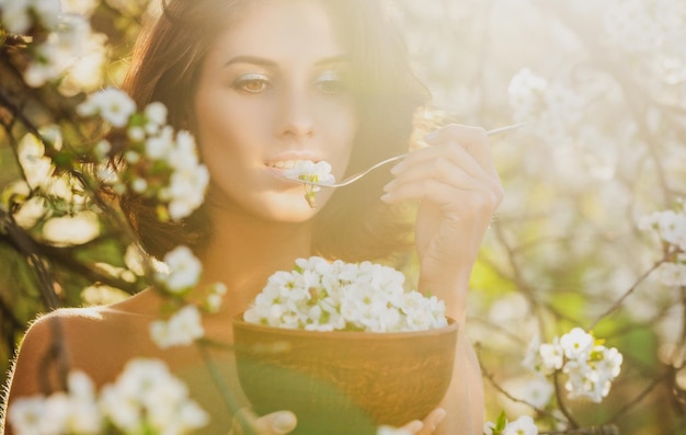 Jolie femme végétalienne avec plat de feuilles de fleurs de cerisier Concept d'alimentation saine Régime végétarien