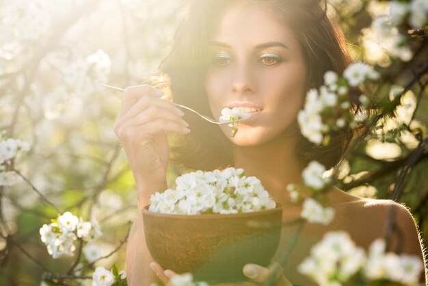 Jolie femme végétalienne avec un plat de fleur de cerisier laisse un concept d'alimentation saine suivant un régime végétarien