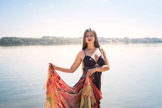 Jolie femme vêtue d'une robe posant sur la plage