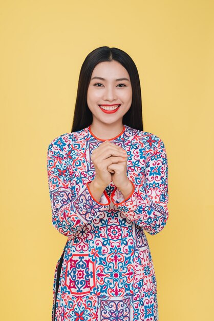 Jolie femme vietnamienne en costume traditionnel, isolée sur fond jaune