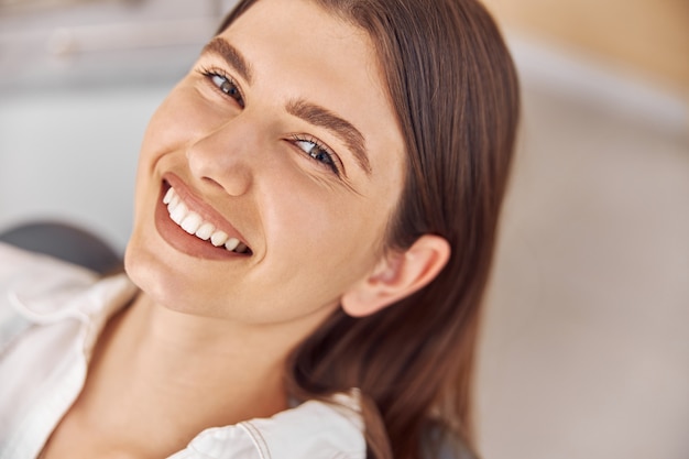 Jolie femme visitant une clinique dentaire. Heureuse jeune femme assise dans un fauteuil dentaire au bureau du dentiste.