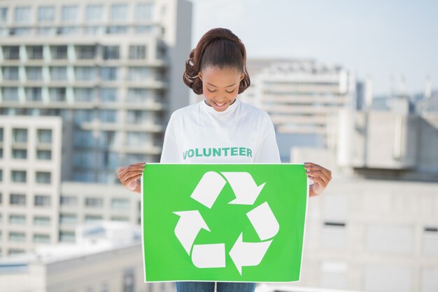 Jolie femme volontaire tenant un panneau de recyclage