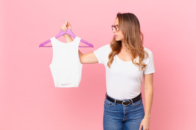 Jolie femme sur la vue de profil pensant, imaginant ou rêvant et choisissant des vêtements