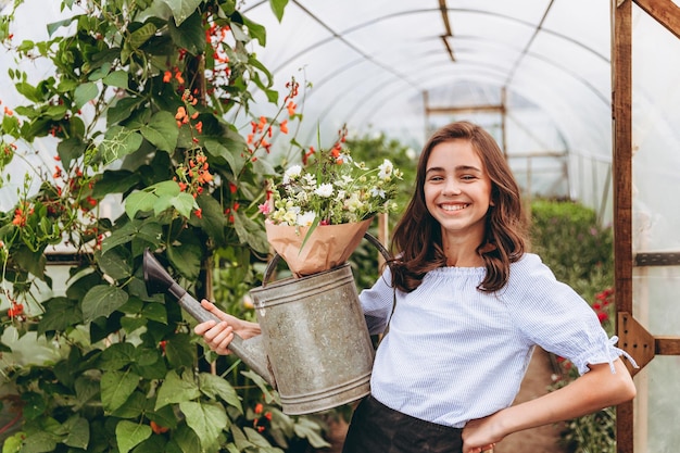 Jolie fille de 13 ans portant un panier de belle fleur dans le champ de fleurs avec bonheur