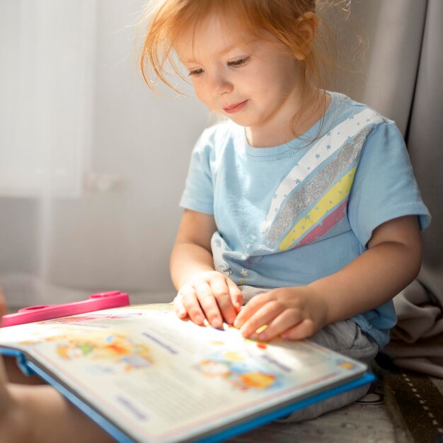 Photo jolie fille 23 avec intérêt regarde le livre assis à la maison