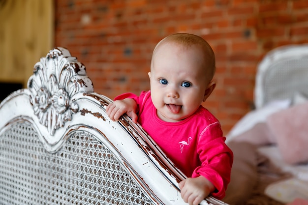 Jolie fille 6monthold heureuse aux yeux bleus en robe rouge vif à la tête