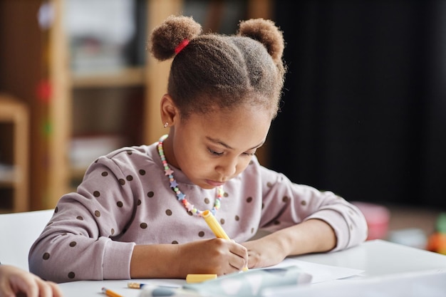 Jolie fille afro-américaine sérieuse dessinant avec un surligneur jaune