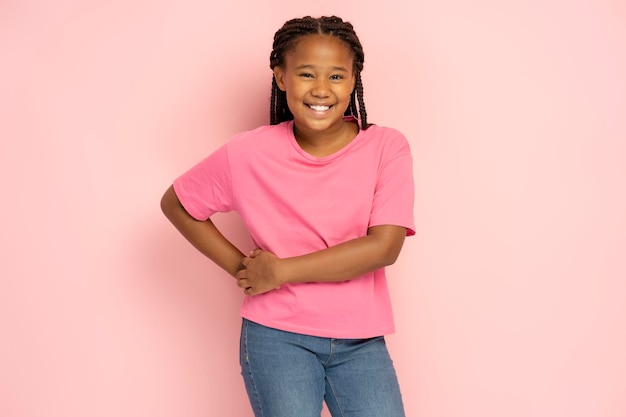 Jolie fille afro-américaine souriante portant un t-shirt rose décontracté isolé sur fond rose