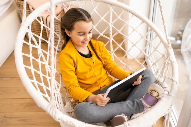 Jolie fille allongée sur un canapé avec tablette.