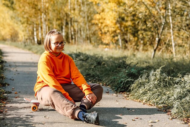 Jolie fille apprenant à faire du skateboard à l'extérieur par une belle journée d'automne