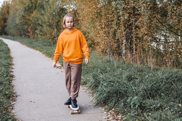 Jolie fille apprenant à faire de la planche à roulettes à l'extérieur par une belle journée d'automne