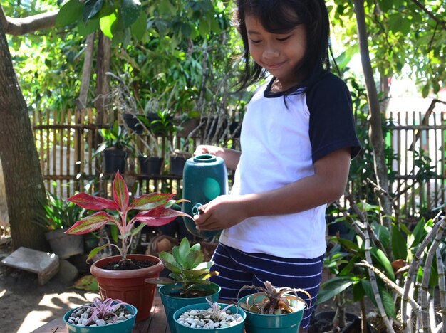 Photo une jolie fille arrose les plantes dans le jardin.