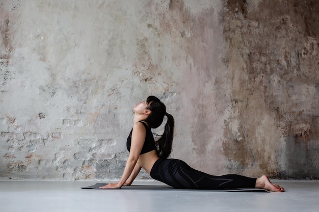 jolie fille asiatique aux cheveux longs foncés dans des leggings de vêtements de sport d'entraînement et haut faisant du yoga