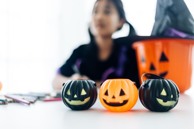 Jolie fille asiatique en costume de sorcière faisant une jackolantern pour la fête d'Halloween