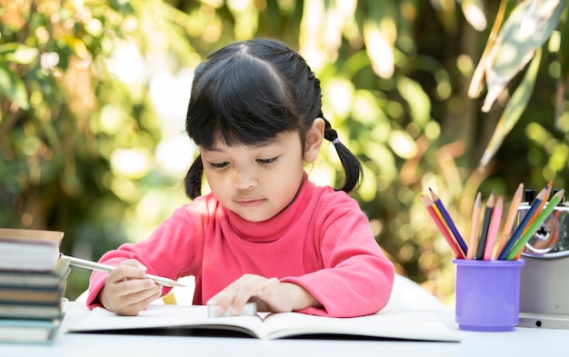 Jolie fille asiatique écrit le livre à la maison