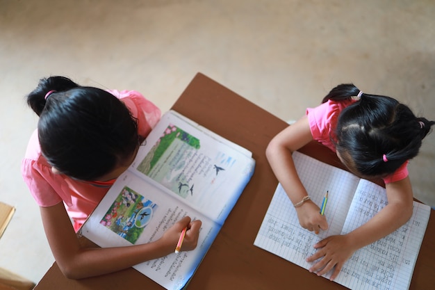 Une jolie fille asiatique fait ses devoirs dans sa maison pendant la journée