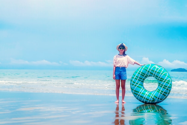 Jolie fille asiatique sur la plage de la mer d'été tenant l'anneau de bain