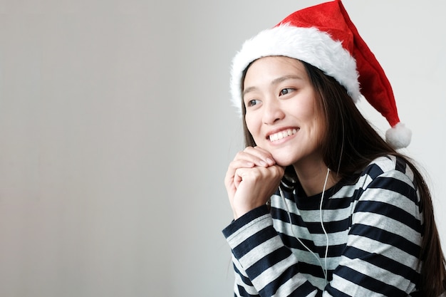 Jolie fille asiatique portant un chapeau de Noël avec un visage souriant