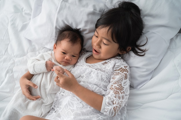 Jolie fille asiatique portant sur le lit avec son petit frère