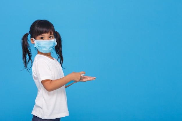 Jolie fille asiatique portant un masque et se laver les mains avec de l'alcool