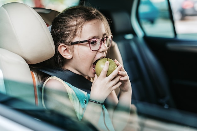 Jolie fille assise dans une voiture sur un siège auto pour enfant de sécurité.