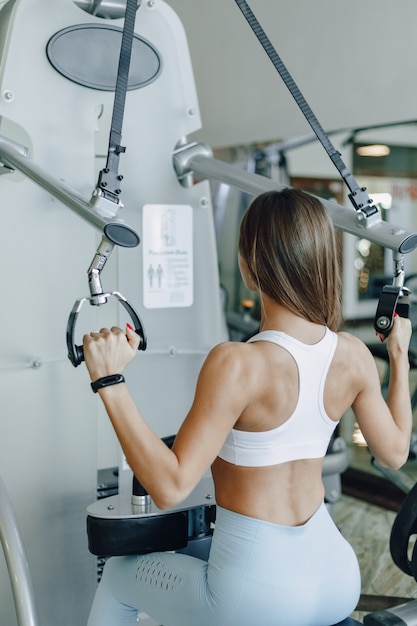 Jolie fille athlétique entraîne les épaules dans le simulateur. vue des muscles du dos. mode de vie sain.